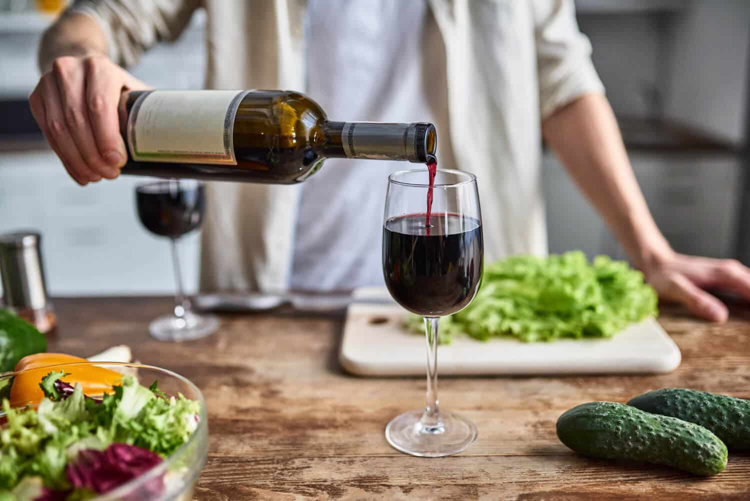 close-up-man-kitchen-pours-wine-into-glass-prepares-salad-1