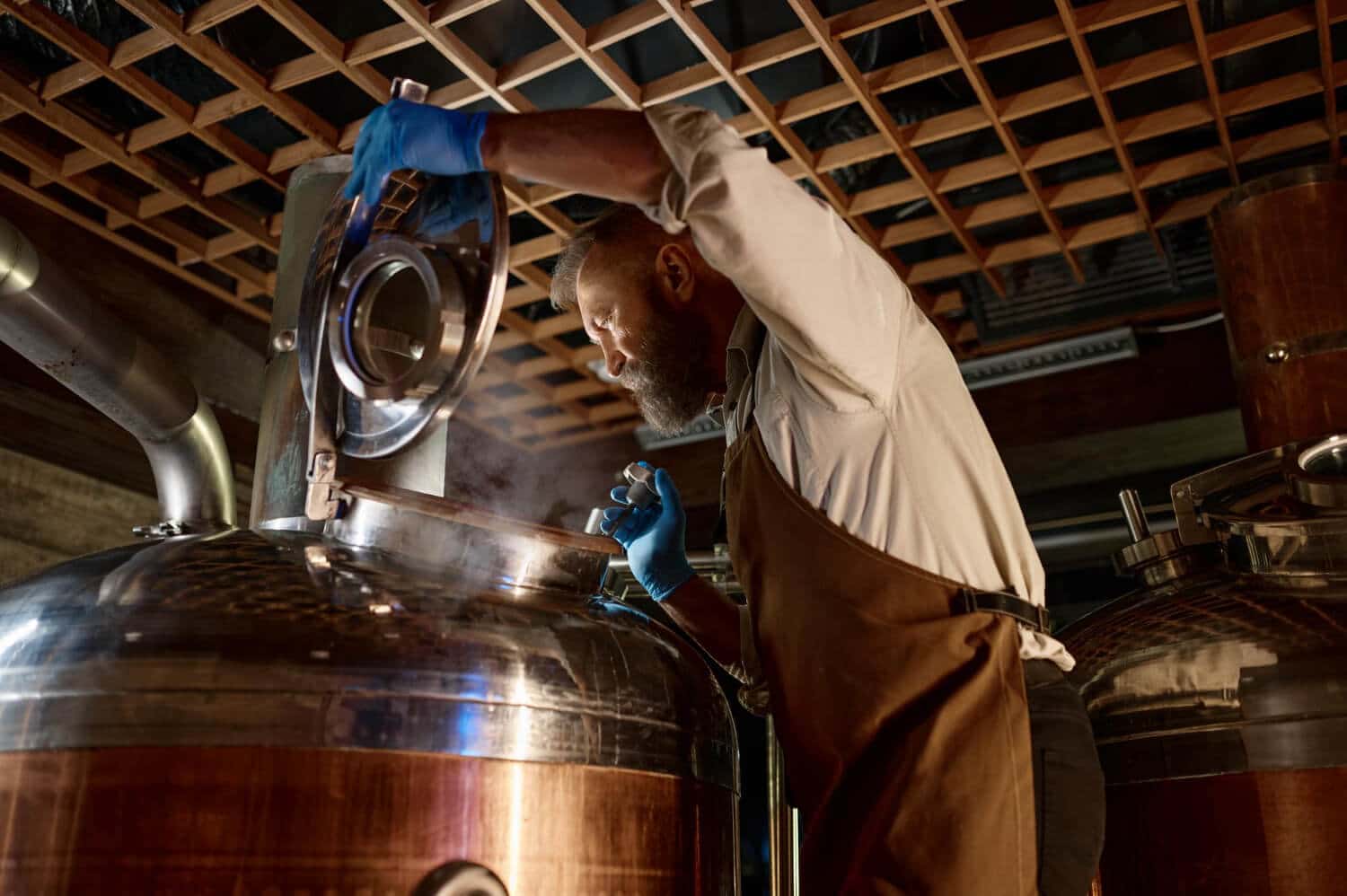 handsome-adult-brewer-inspecting-process-brewing-beer-with-steam-small-brewery-factory-family-business-concept-1